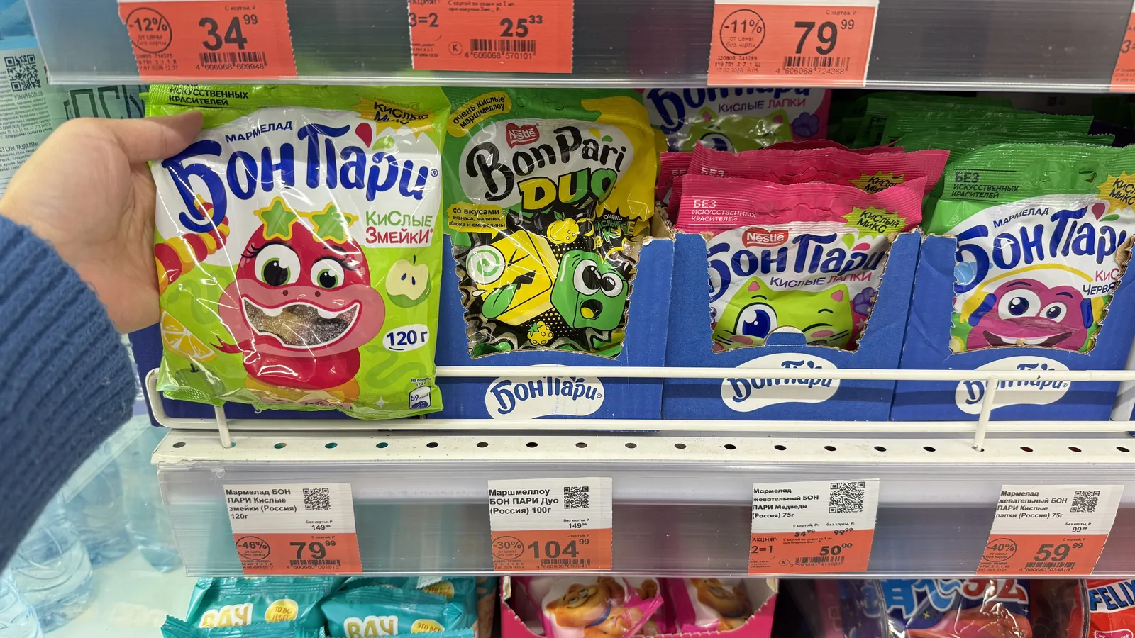 Une cliente décroche un sachet de confiserie d'un linéaire de proximité — le moment d'impulsion pour lequel les gommes au café sont conçues